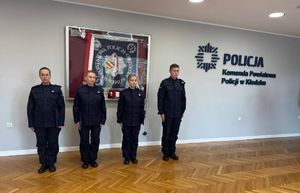 czworo policjantów stoi przy gablocie ze sztandarem -policjant oraz trzy policjantki