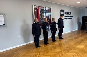 czworo policjantów stoi przy gablocie ze sztandarem w tele na ścianie napis komenda Powiatowa Policji w Kłodzku