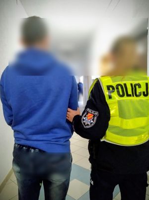 policjantka prowadzi zatrzymanego mężczyznę w pomieszczeniu policyjnym