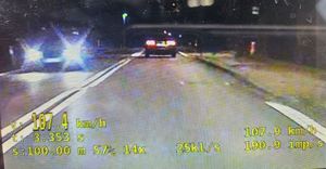 zdjęcie auta osobowego z napisem prędkości 107 km/h  zdjęcie wykonane w nocy, obok jedzie inne auto osobowe
