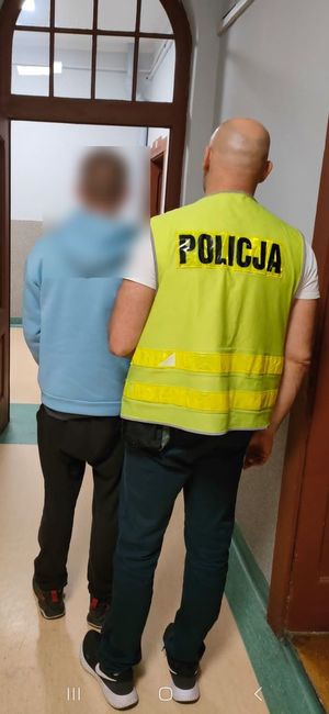 policjant w pomieszczeniu służbowym prowadzi zatrzymanego chłopca