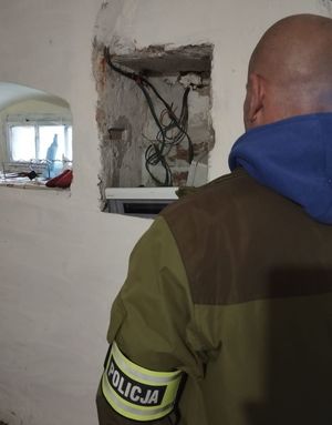 policjant stoi w pomieszczeniu widać wiszące przewody na ścianie