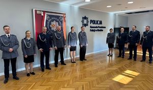 grupa policjantów stoi w sali i widać fragment napisu na ścianie