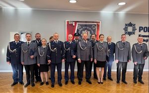 grupa policjantów i ich przełożonych stoi w sali i widać fragment napisu na ścianie