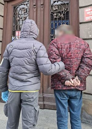 policjant prowadzi zatrzymanego do budynku urzędu - sadu