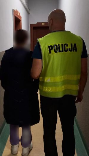 policjant prowadzi zatrzymaną kobietę