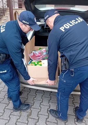 dwóch policjantów wyciąga z bagażnika radiowozu policyjnego prezenty