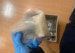 policjant trzyma w ręku z rękawiczką  woreczek , widać fragment wagi