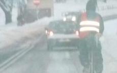 rowerzysta i samochód jadą po ośnieżonej drodze