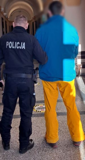 policjant prowadzi zatrzymanego mężczyznę