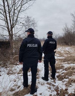dwóch policjantów stoi obok sienie dookoła leży śnieg