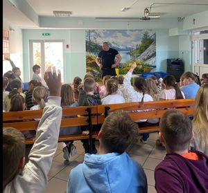 policjant stoją przy grupie dzieci i rozmawiają