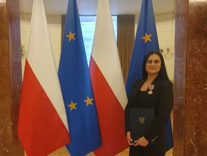 kobieta stoi przy flagach , trzyma w rece teczkę