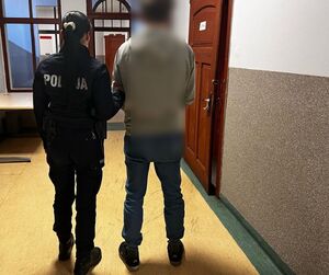 policjantka  prowadzi zatrzymanego mężczyznę  w pomieszczeniu służbowym policji