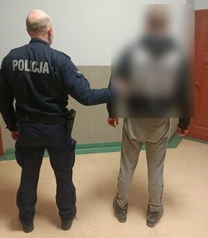 policjant prowadzi zatrzymanego mężczyznę  w pomieszczeniu służbowym policji