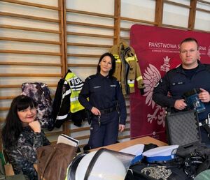 mundurowi stoją przy stolikach na których znajduje sie sprzęt służb. Zdjęcie wykonane w pomieszczeniu - sala sportowa