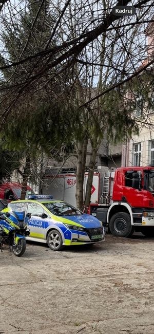 pojazdy służbowe munduriwych służb zaparkowane pzred budynkeim szkoły