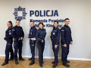 grupa policjantów i policjantek stoi w sali sztabowej na ścianie napis Komenda Powiatowa Policji w Kłodzku