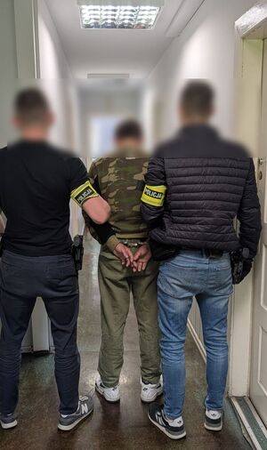 dwóch policjantów prowadzi zatrzymanego mężczyznę