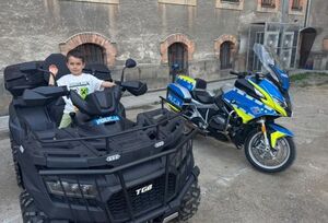 chłopiec siedzi za kierwicia quada i ma podniesianą rękę