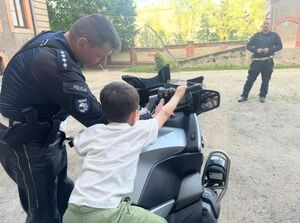 polciajnt stoi pzrych chłopcu który siedzi na motocyklu