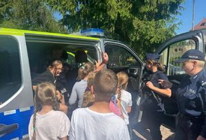 dzieci przy radiowozie policyjnym z policjantka