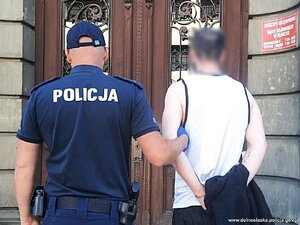 policjant prowadzi zatrzymanego mężczyznę do budynku sądu- pzry wejsciu przy drzwiach tabliczka Sąd Rejonowy w Kłodzku