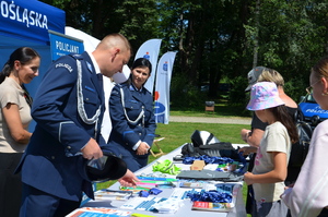 stoisko promocyjne poicyjne i policjanci stojący oraz dzieci