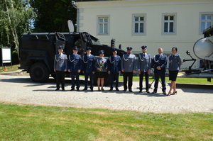 policjanci stoiją pzry specjalistycznym wozie na terenie  pzry budynku