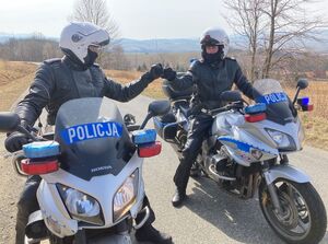 dwóch policjantów siedzi na motocyklach i witają się