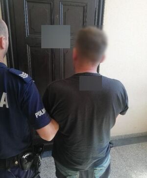 policjant w korytarzu  prowadzi zatrzymanego mężczyznę