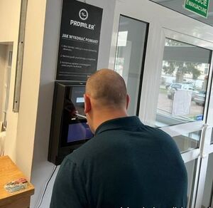 mężczyzna stoi tyłem przy ścianie gdzie jest urządzenie