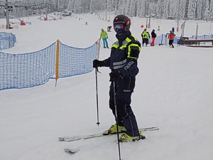 Policjant na nartach na stoku, dookoła lezy śnieg