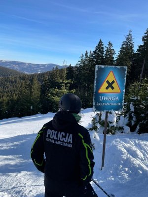 patrol policjanta na nartach na stoku .Dookoła leży Śnieg. Na kamizelce napis patrol narciarski policja