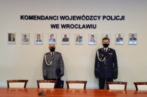 W sali sztabowej Komendy Wojewódzkiej Policji stoi dwóch Komendantów. Z prawej Strony Komendant Wojewódzki Policji we Wrocławiu inspektor Dariusz Wesołowski a z lewej strony Komendant Powiatowy Policji w Kłodzku podinspektor Rafał Siczek. Panowie Komendanci mają na twarzach maseczki. N ścianie widać napis Komendanci Wojewódzcy Policji we Wrocławiu oraz ich zdjęcia .