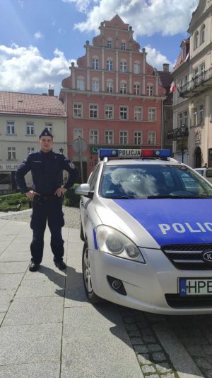starszy posterunkowy Paweł Michoń policjant z Komisariatu Policji w Polanicy zdroju stoi przy radiowozie.